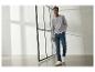 Man in een grijs Henley-shirt met lange mouwen, blauwe jeans en witte sneakers loopt binnen.