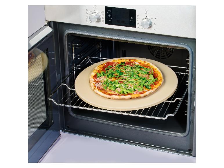 Pizza met rucola en ham op een pizzasteen in een open oven.