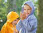 Twee kinderen in regenjassen spelen in de regen.