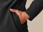 Een close-up van een hand in de zak van een zwarte jas.