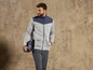 Un homme portant une veste polaire grise avec une couverture bleue à carreaux.