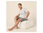 Homme souriant en t-shirt blanc et short bleu assis sur un pouf.