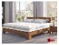 Lit en bois avec deux matelas blancs, table de chevet et fenêtre donnant sur des arbres.