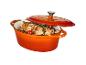 Een oranje braadpan met vlees en groenten.