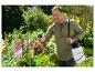 Lachende man gebruikt een Parkside tuinspuit op bloemen.