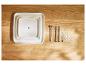 Trois plateaux carrés blancs et accessoires métalliques pour un support à gâteau, sur une table en bois.