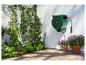 Dévidoir de tuyau PARKSIDE sur un mur blanc, avec des plantes et des fleurs en pot dans un jardin.