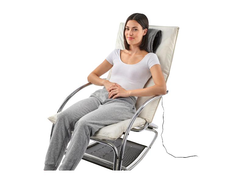 Une femme assise dans un fauteuil relax blanc avec un coussin de massage.