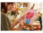 Une femme peint à l'acrylique un tableau de fleurs dans un vase.