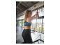 Femme en tenue de sport noire faisant de l'exercice sur un appareil de fitness.