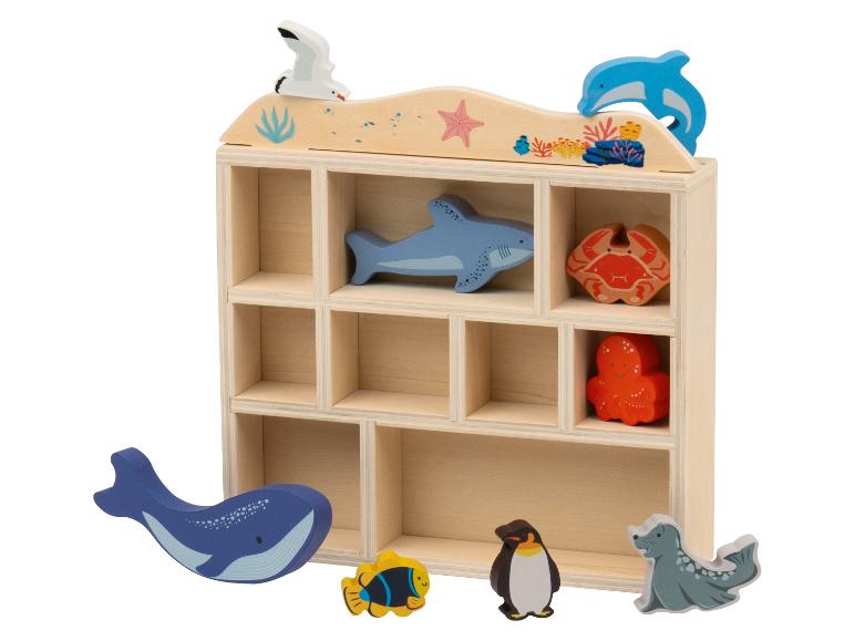 Étagère en bois avec des animaux marins en bois, dont une baleine, un requin et un crabe.