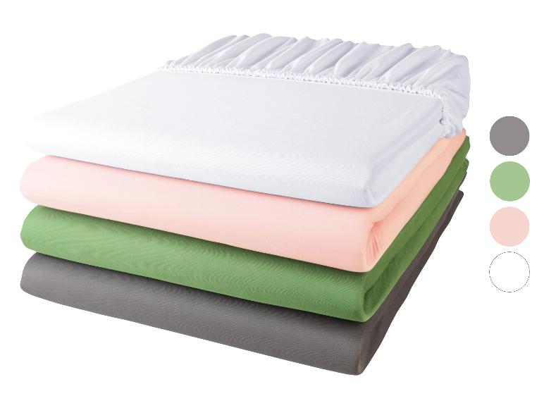 Draps-housses empilés : blanc, rose, vert et gris.