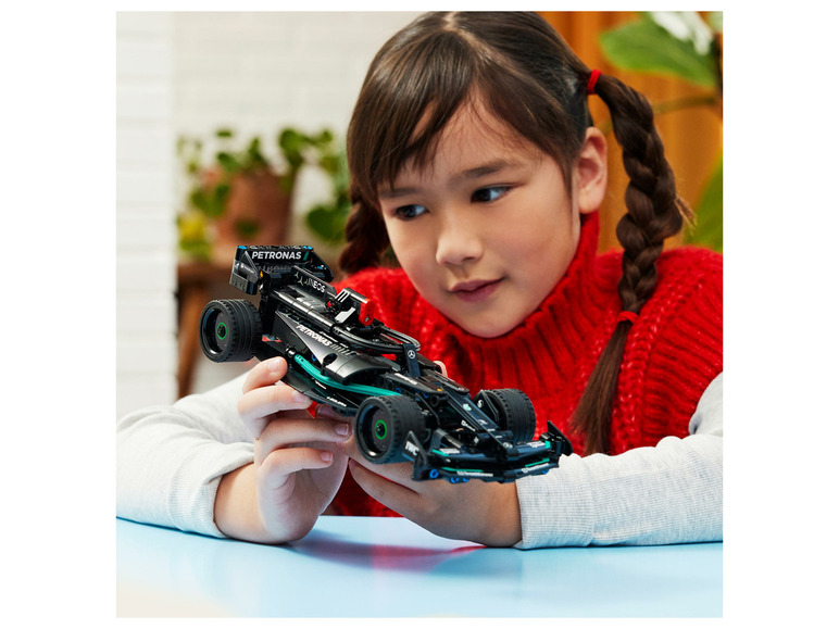 Een kind bekijkt een LEGO® Technic™ Mercedes-AMG Petronas F1™ W12-auto.
