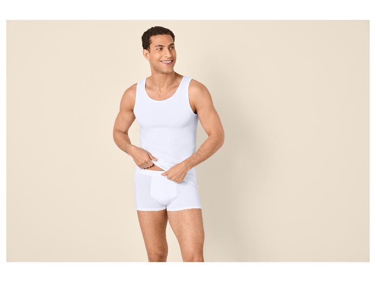 Man in wit hemd en boxershort, lachend en opzij kijkend.