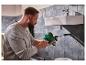 Homme utilisant un furet de plomberie vert dans la salle de bain.