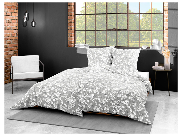 Une literie grise avec un motif floral blanc, y compris des taies d'oreiller.