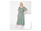 Blonde vrouw in saliegroene maxi-jurk met ceintuur en witte sneakers
