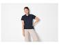 Lachende vrouw in een marineblauwe poloshirt en beige broek.