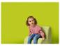 Lachend meisje in roze sweatshirt en jeans zit op een groene fauteuil