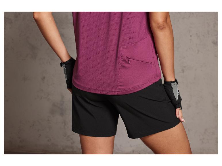 Une femme porte un t-shirt de sport violet et un short noir.