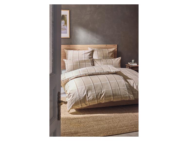 Chambre avec housse de couette et taies d'oreiller à carreaux beiges, tête de lit en bois et tapis en jute.
