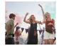 Festivalgangers dansen in boho kleding en tassen.