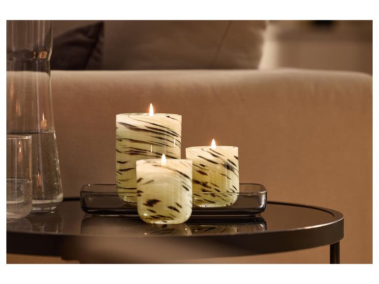Drie decoratieve kaarsen met zebraprint en een glazen kan op een bijzettafel.