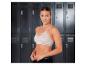 Femme en brassière de sport rose clair et short noir dans un vestiaire.
