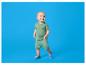 Lachende baby in een groen setje met zonnepatroon en blauwe schoentjes.