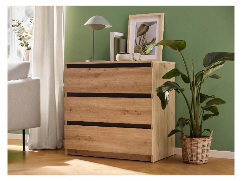 Houten ladekast met drie lades, naast een bank, gordijnen en planten.