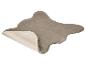 Tapis gris en fausse peau de mouton avec un bord plié montrant le dessous clair.