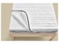 Wit matras met open rits, toont de binnenste schuimlaag, op een houten bedframe.