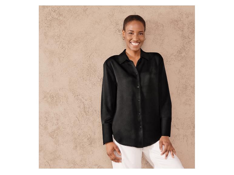Een vrouw draagt ​​een zwarte satijnen blouse.