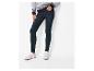 Femme en pull gris à motifs et jean skinny bleu avec baskets blanches.
