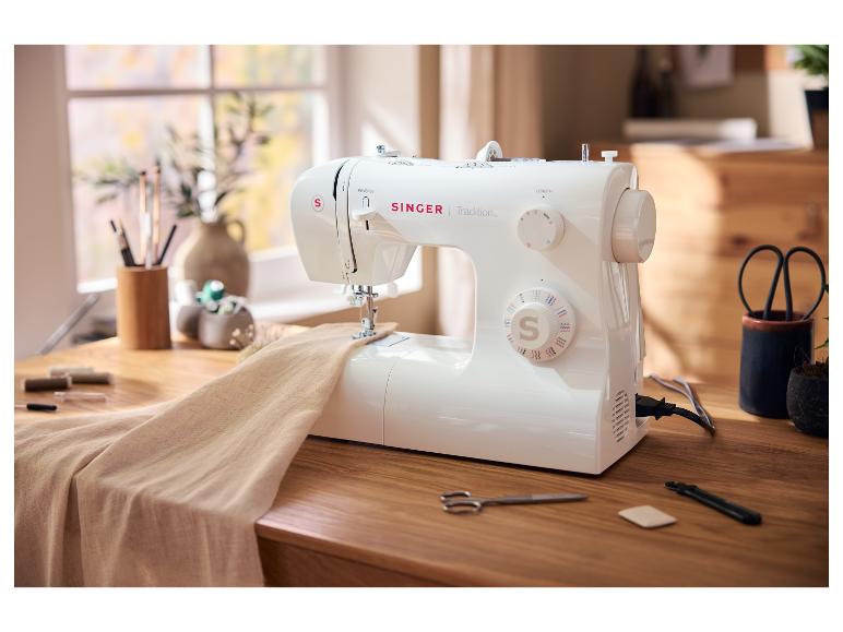 SINGER Tradition naaimachine op een houten tafel met stof en naaibenodigdheden.