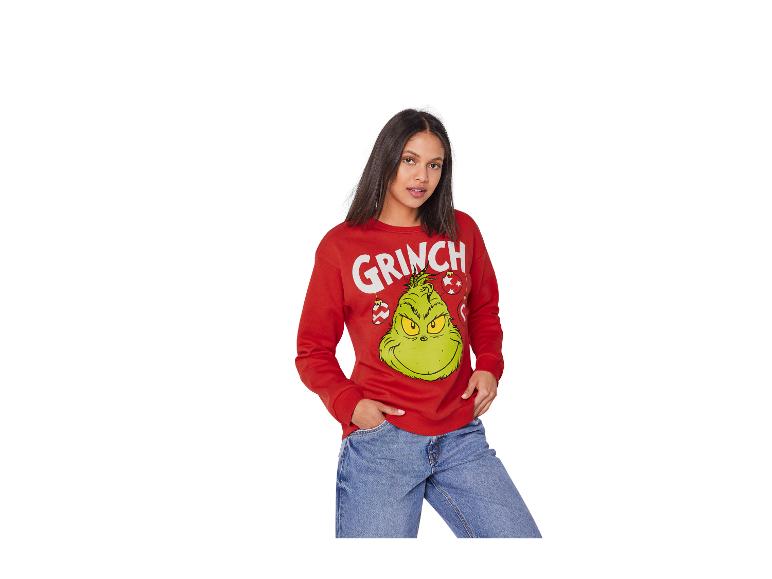 Vrouw in rode Grinch trui en blauwe jeans