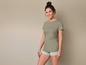Een vrouw draagt ​​een groene T-shirt en gestreepte shorts.