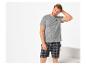 Man in een grijs T-shirt met 'Be My Valentine?' tekst en geruite shorts.