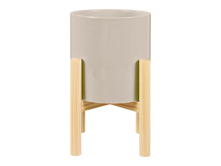 Een grijze bloempot op een houten standaard.