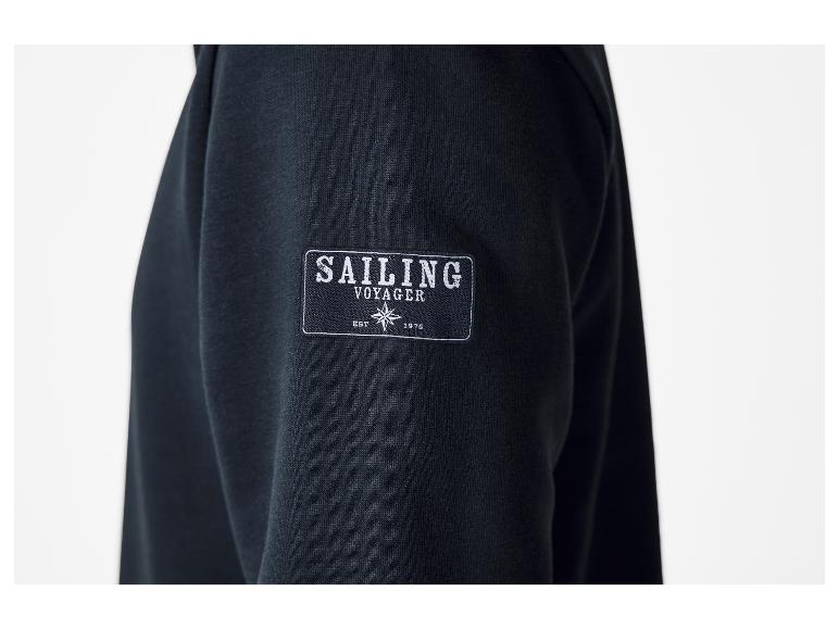 Manche de sweat-shirt noir avec un écusson 'SAILING VOYAGER EST 1976' et une rose des vents.