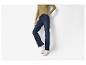 Vrouw draagt olijfgroene ribtop en donkerblauwe jeans met witte sneakers