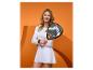 Vrouw in witte sportkleding met padelracket tegen oranje achtergrond.