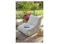 Pouf d'extérieur beige avec magazine, plantes et lanterne sur un tapis.