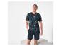 Man in donkerblauw T-shirt met tropische print en korte broek, lachend.