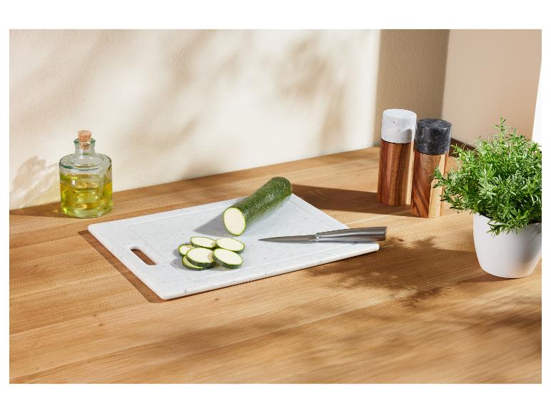 Gesneden courgette op een snijplank, met olijfolie en kruiden.