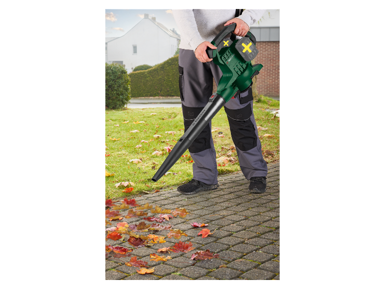 Een man gebruikt een Parkside bladblazer om herfstbladeren op te ruimen.