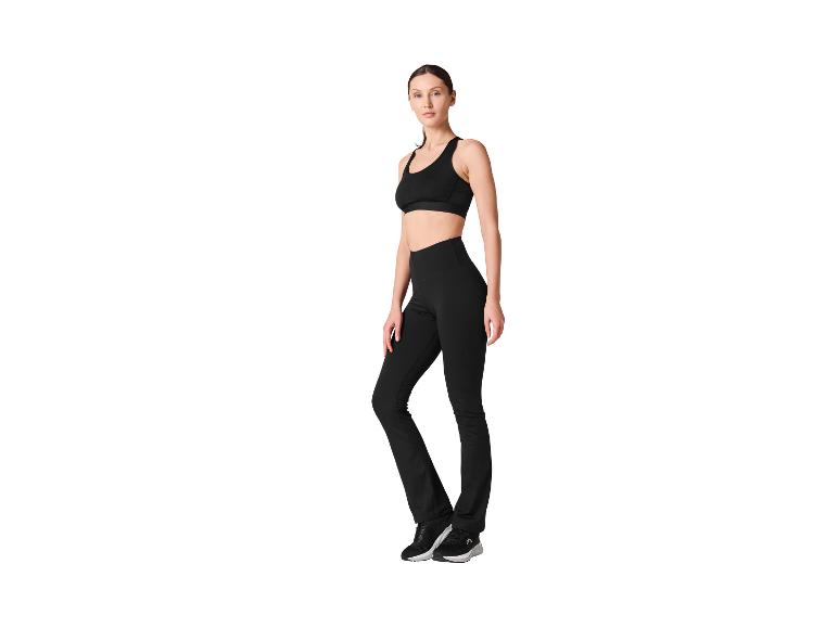 Vrouw in zwarte sportkleding, bestaande uit een sportbeha en legging.