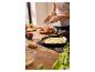 Personne préparant des crêpes aux fruits rouges et au sucre dans une poêle en cuisine.
