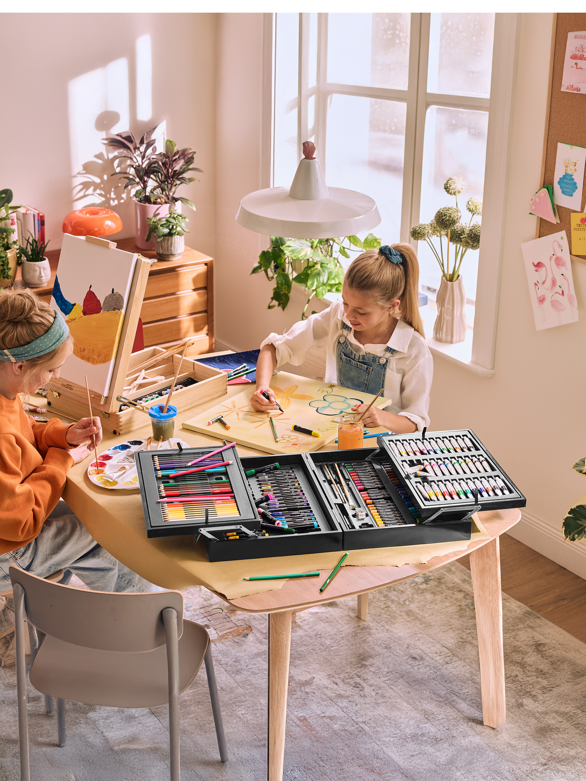 Deux filles peignent à une table avec des kits d'art Crelanado.