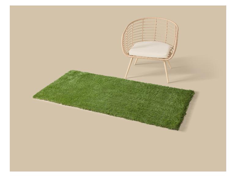 Tapis d'herbe artificielle verte avec une chaise en osier et coussin.